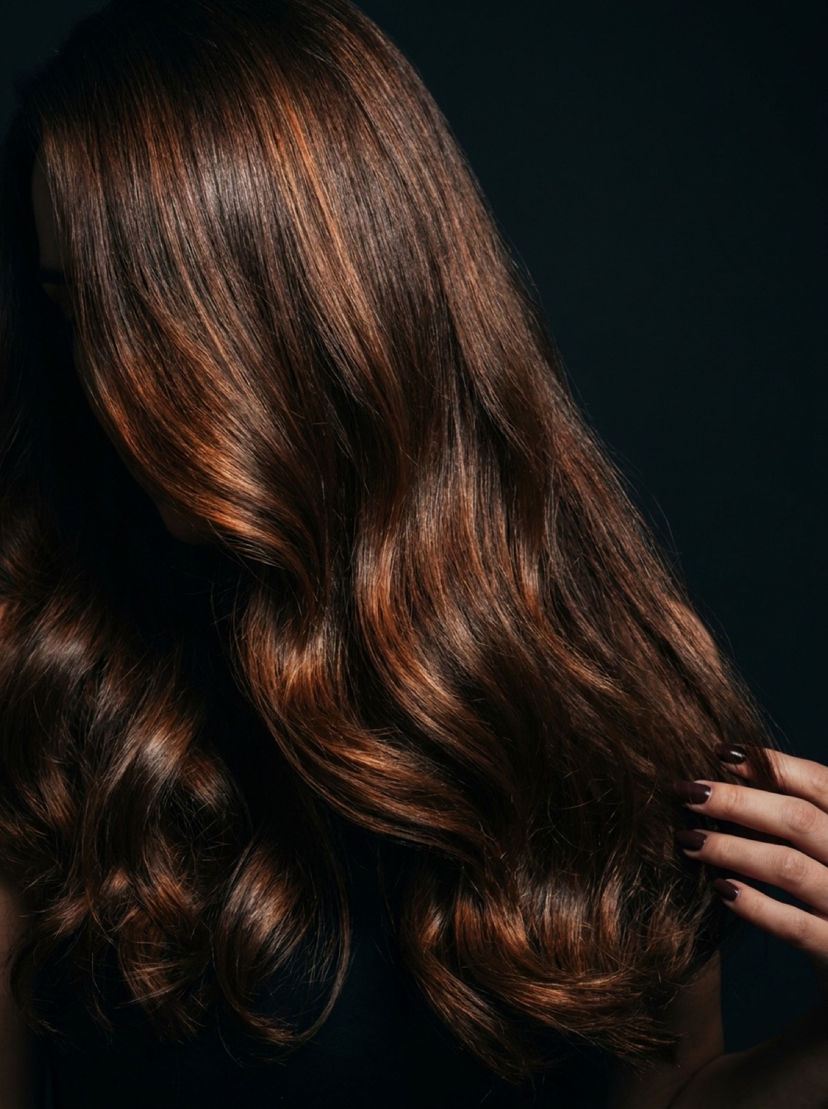 Cascading voluminous brunette waves with warm copper highlights